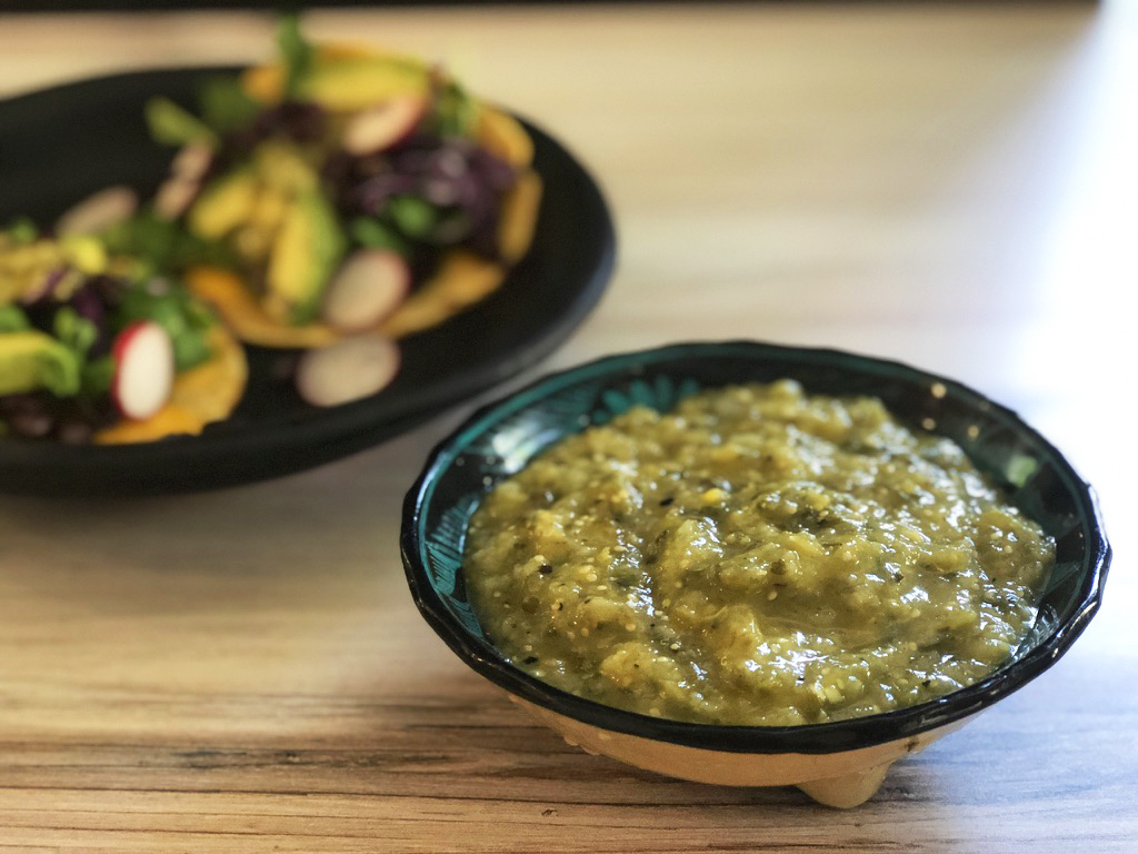tomatillo salsa verde with veggie tacos in background