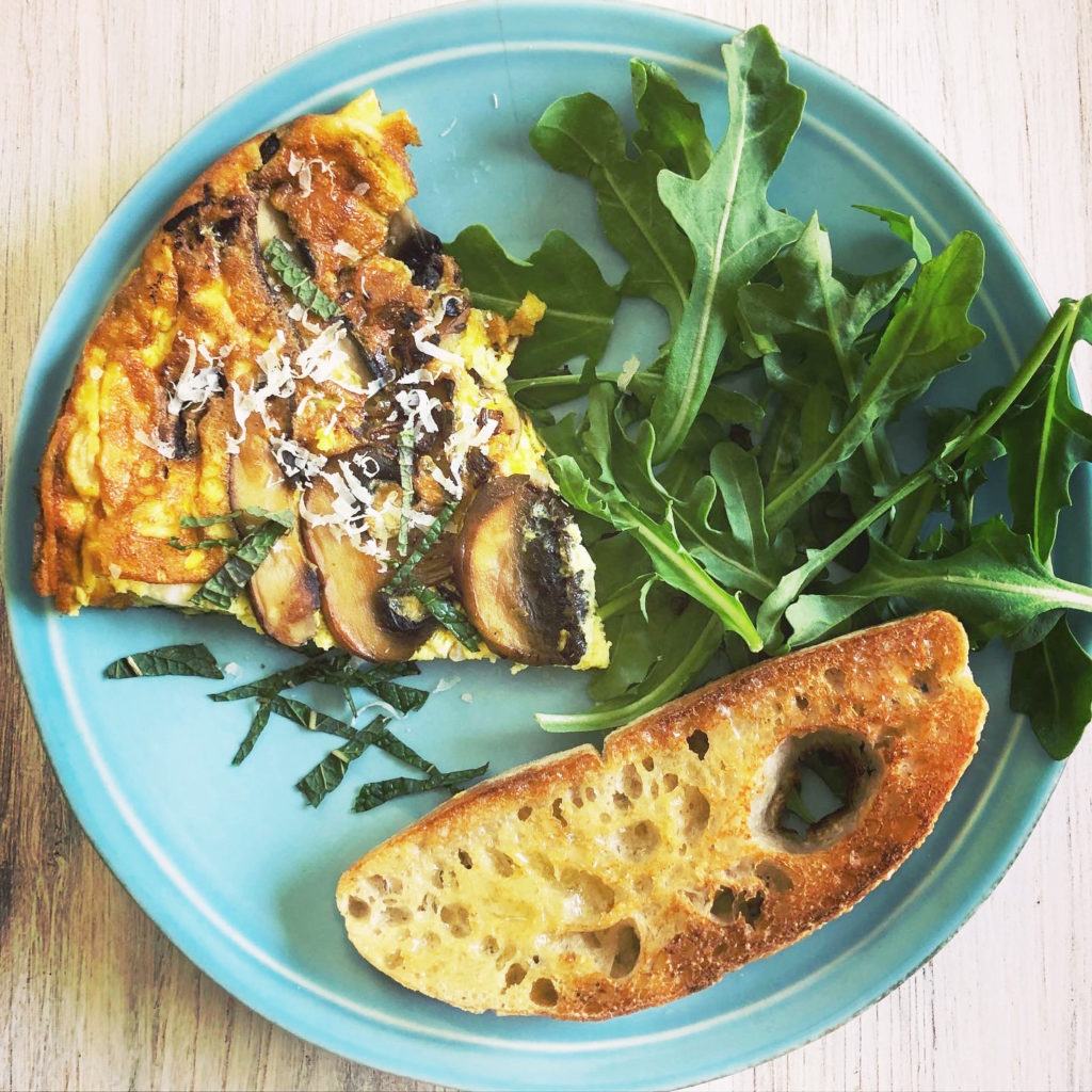 Mushroom Frittata with Gruyere Cheese on late with toasted bread and arugula salad