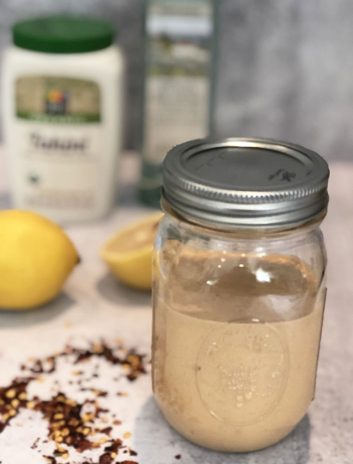 Lemon Tahini Dressing with ingredients in background