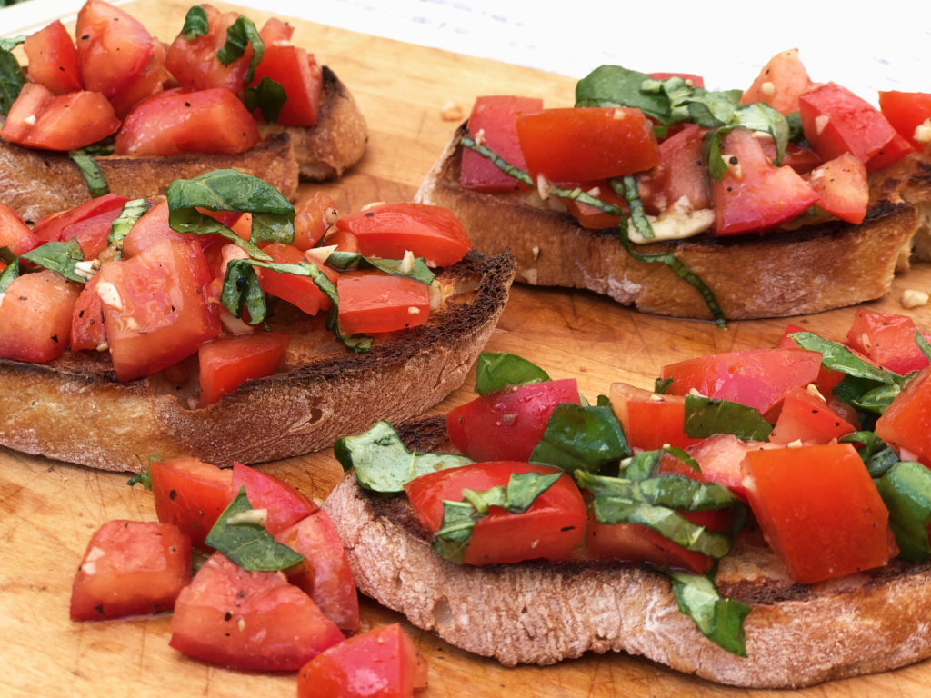 Summer appetizer: Bruschetta with Tomato and Basil served on wooden platter