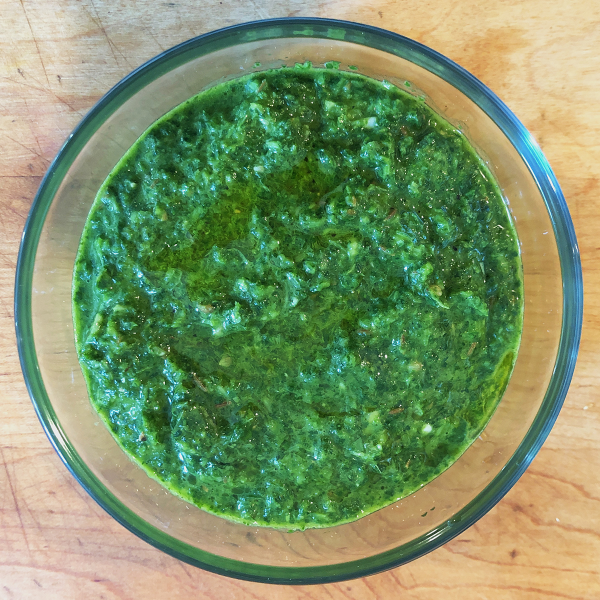 Green Shug Hot Sauce in glass bowl on wood surface