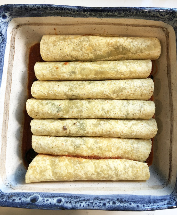 Tortilla with black beans and kale rolled up in pan