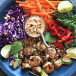 Chicken Meatballs with Peanut Sauce served on a platter with thinly sliced carrots, purple cabbage and arugula